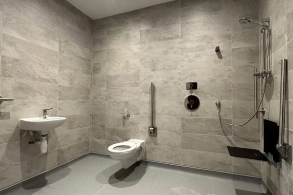 a large accessible shower room with toilet and sink